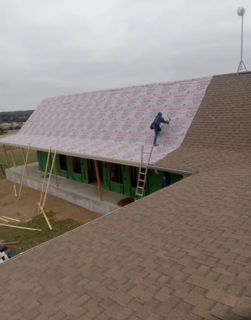 Worker preparing underlayment for a metal roof installation in Haddam
